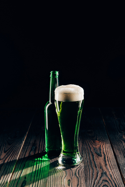 светящееся стекло и бутылка зеленого пива на деревянном столе, День святого Патрика
 - Фото, изображение