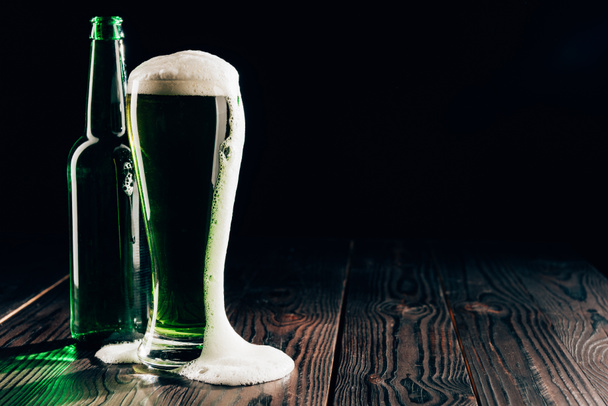 vidro e garrafa de cerveja verde com espuma na mesa, st patricks conceito dia
 - Foto, Imagem