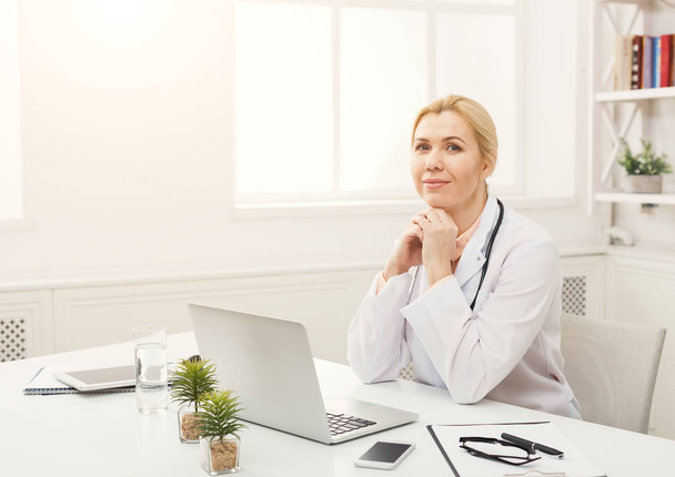 Portrait of female doctor sitting at the desktop - Foto, afbeelding