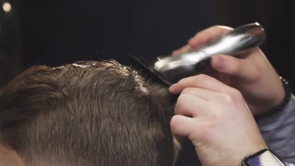 Przycięte zbliżenie Fryzjer ścinania włosów jego klienta z trymer - Materiał filmowy, wideo