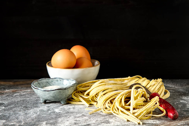 Homemade italian tagliatelle with flour. Dark background. - Foto, Bild