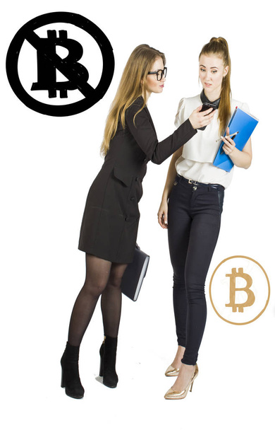 Beautiful women standing over white background with bitcoin sketches and talking. Virtual money concept. Cryptocurrency - 写真・画像