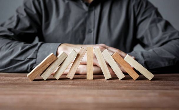 Stopping domino effect with one wood domino. Security and insurance concept. - Foto, imagen