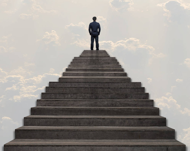Επιχειρηματίας που στέκεται για περπάτημα μέχρι το σκάλες πάνω από το σύννεφο και τον ουρανό φόντο, επιχειρηματική επιτυχία και φιλοδοξίες έννοια - Φωτογραφία, εικόνα