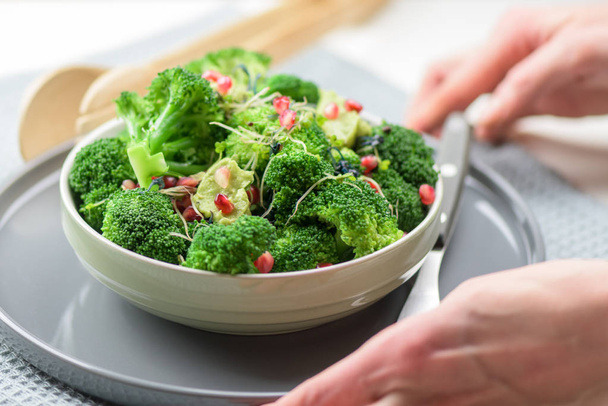 Broccoli salad with pomegranate and guacamole - hands holding healthy meal. - Photo, Image