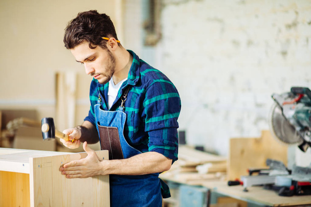 carpenter hammering a nail into wooden board - Fotografie, Obrázek