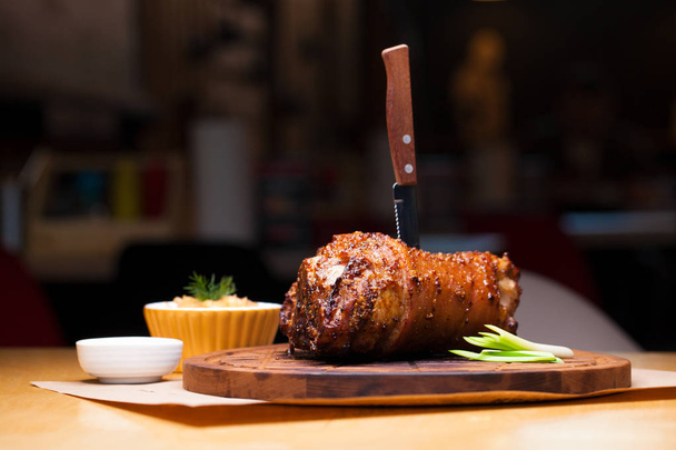 Restaurant dish - large baked pork knuckle on a wooden tray - Foto, imagen