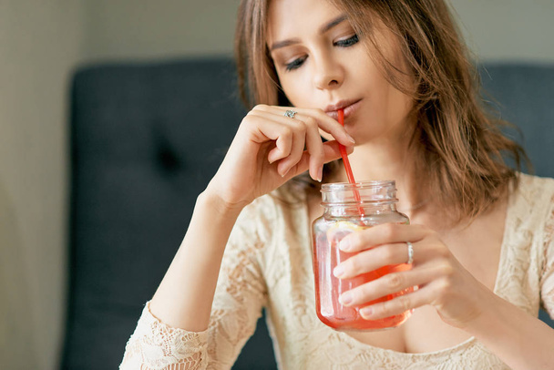 Yong beautiful woman drinks strawberry lemonade with red drinking straw - Φωτογραφία, εικόνα