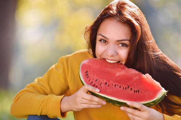 Happy young woman bite slice of ripe watermelon in the park - Photo, Image
