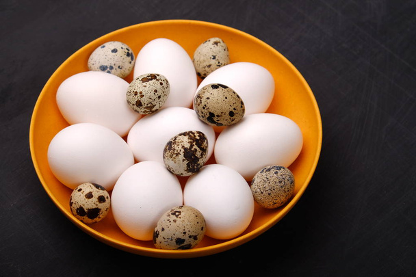 Close up of easter chicken and quail eggs in dish on dark background - Photo, image