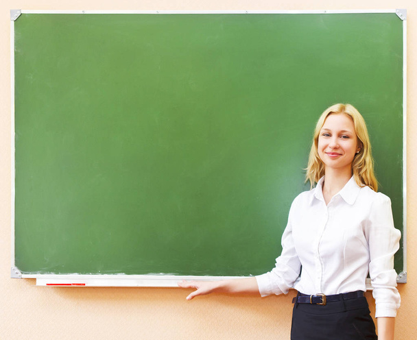 Estudante menina de pé perto de quadro negro na sala de aula
 - Foto, Imagem