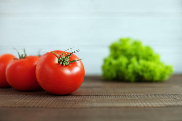 Tomates e alface em uma mesa de madeira. O conceito de saudável e
 - Foto, Imagem