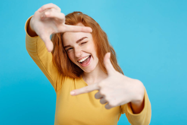 Portrait of young beautiful ginger woman with freckles cheerfuly smiling making a camera frame with fingers. Isolated on white background. Copy space. - Photo, Image