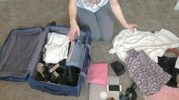 woman collects a suitcase in a home room. - Video