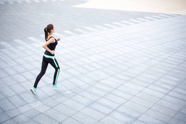 Young woman jogging in city copy space - Фото, изображение