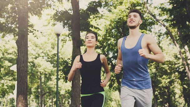 Fiatal nő és férfi zöld parkban, másol hely jogging - Fotó, kép