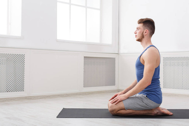 Yoga d'entraînement d'homme dans la pose de héros, vue latérale
 - Photo, image