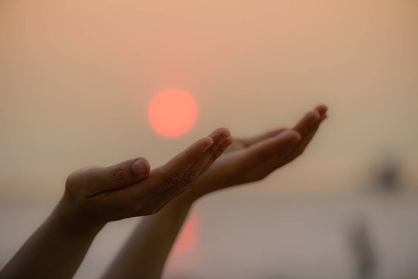 Primeros planos de las manos de la mujer rezando por la bendición de Dios durante la puesta del sol
 - Foto, Imagen