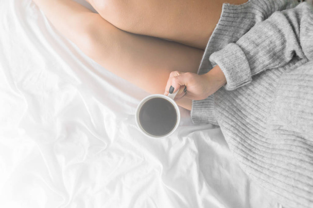 タブレットとベッドの上の女性の柔らかい写真と手でのコーヒーのカップ、トップ ビュー ポイント コピー スペース平面図ホワイト光着色 - 写真・画像
