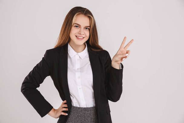 Portrait of beautiful young business woman with a peace sign on gray background. Copy space - Foto, immagini