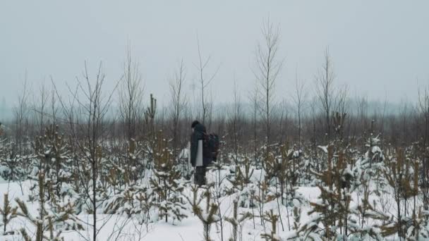 Genç adam karda yürümek çayır "Bahçe Çiti" kış gününde kaplı. - Video, Çekim