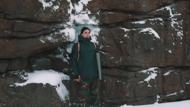 Joven posando frente a la pared del acantilado cubierto de nieve
 - Imágenes, Vídeo