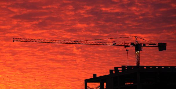 κτίριο γερανός σε φόντο κόκκινο ουρανό - Φωτογραφία, εικόνα
