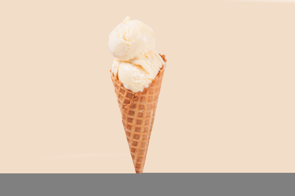 Vanilla ice cream cone on faded pastel color background. - Photo, Image