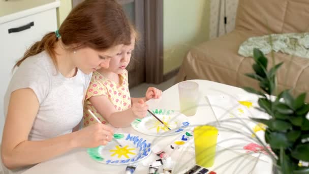 Familia feliz, madre e hija pequeña pintan con pintura en platos blancos
 - Imágenes, Vídeo