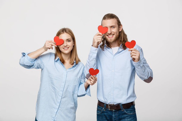 attraktives junges verliebtes Paar mit roten Herzen über den Augen auf weißem Hintergrund - Foto, Bild