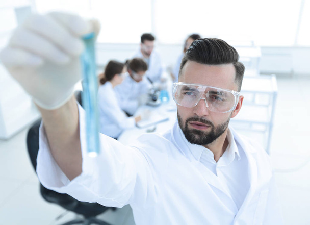 image is blurred. young scientist holding tube with the reagents - Photo, Image