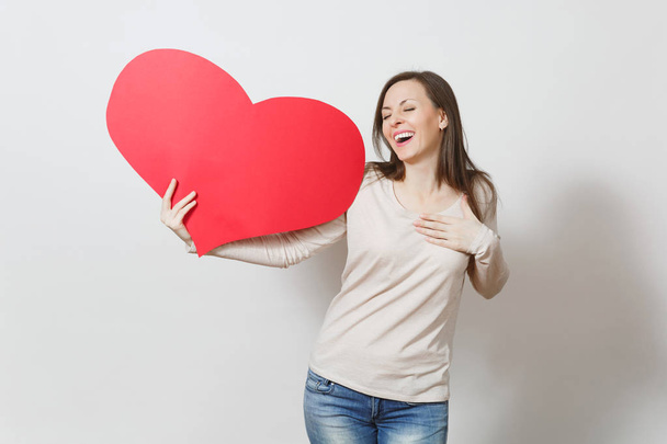 Pretty fun young smiling woman holding big red heart in hands is - Fotografie, Obrázek