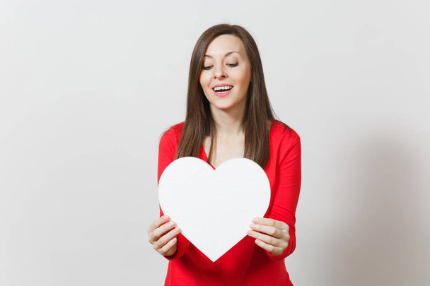 Pretty woman in red clothes holding big white heart in hands isolated on white background. Copy space for advertisement. With place for text. St. Valentine's Day or International Women's Day concept. - Photo, Image