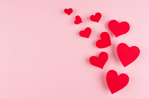 Stream of red paper hearts on soft pink color background, copy space. Valentines day art. - Foto, afbeelding