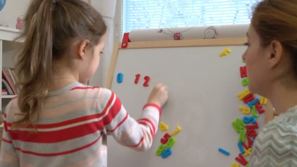 młoda matka wyjaśniający arytmetyki do cute córeczka w domu - Materiał filmowy, wideo