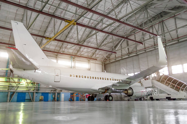 Avion de passagers dans le hangar, moteurs fermés et passerelle à l'entrée de l'avion
. - Photo, image