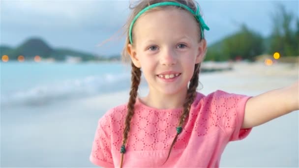Adorable niñita haciendo selfie en la playa tropical blanca. MOCIÓN LENTA
 - Imágenes, Vídeo