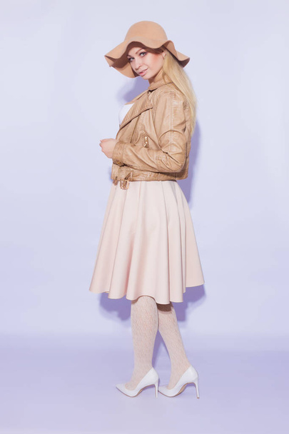Portrait in full length  beautiful young blond woman. The girl dressed in  midi beige skirt and brown short jacket. On her head is  brown hat. On  legs lace stockings and white shoes with heel - Photo, image
