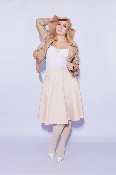 Portrait in full length  beautiful young blond woman. The girl dressed in  midi beige skirt and brown short jacket. On her head is  brown hat. On  legs lace stockings and white shoes with heel - 写真・画像