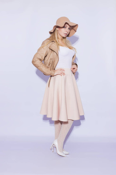 Portrait in full length  beautiful young blond woman. The girl dressed in  midi beige skirt and brown short jacket. On her head is  brown hat. On  legs lace stockings and white shoes with heel - Fotó, kép