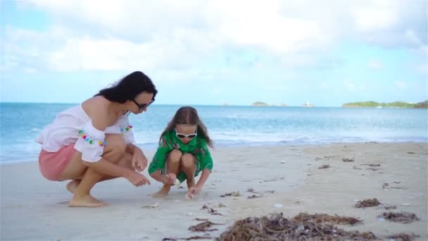 Beautiful mother and daughter on Caribbean beach looking for seashells - Footage, Video