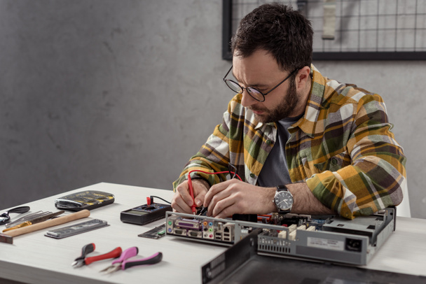Reparateur mit Multimeter beim Reparieren des Computers  - Foto, Bild