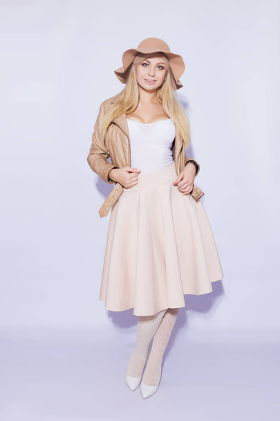 Portrait in full length  beautiful young blond woman. The girl dressed in  midi beige skirt and brown short jacket. On her head is  brown hat. On  legs lace stockings and white shoes with heel - Zdjęcie, obraz