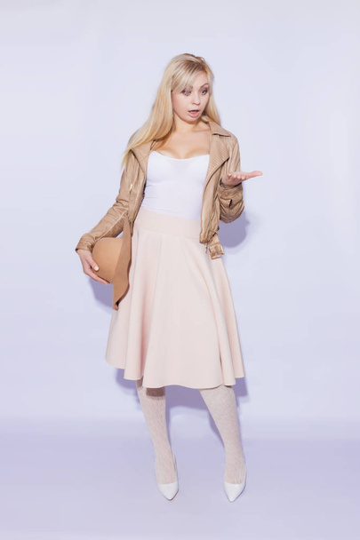 Portrait in full length  beautiful young blond woman. The girl dressed in  midi beige skirt and brown short jacket.With  brown hat. On  legs lace stockings and white shoes with heels.Shocked emotion girl - Photo, image
