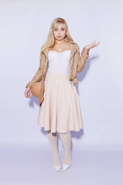 Portrait in full length  beautiful young blond woman. The girl dressed in  midi beige skirt and brown short jacket.With  brown hat. On  legs lace stockings and white shoes with heels.Shoked emotion girl - Photo, image
