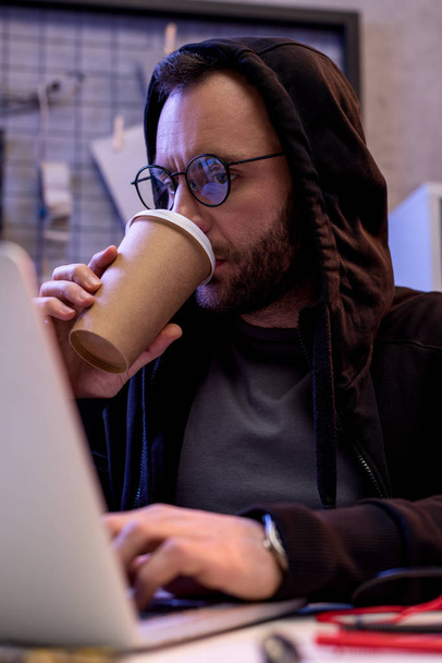 Άνθρωπος πίνει καφέ και χρησιμοποιώντας φορητό υπολογιστή  - Φωτογραφία, εικόνα