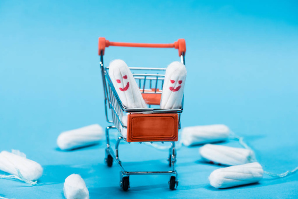 tampons with happy smileys in small shopping cart on blue - Photo, Image