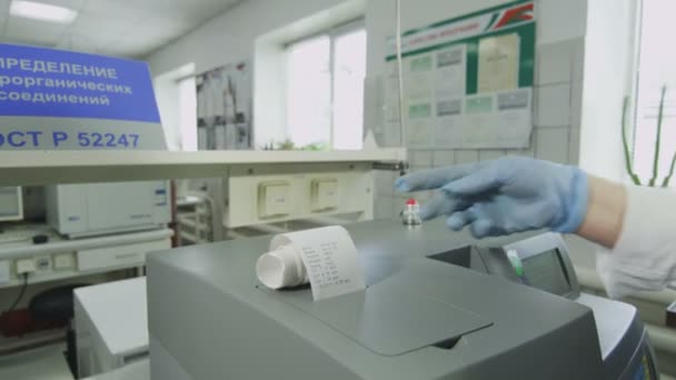 skilled lab assistant looks at finding chemical composition on paper piece from modern device in researching laboratory - Záběry, video