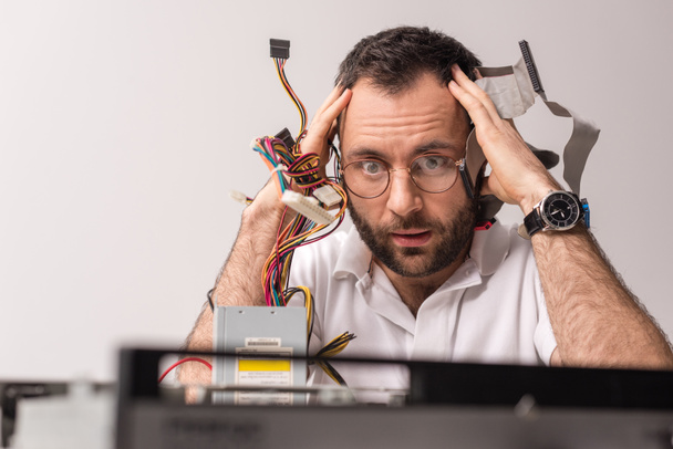 испуганный человек с проводами в руках рядом с головой глядя на сломанный ПК
 - Фото, изображение