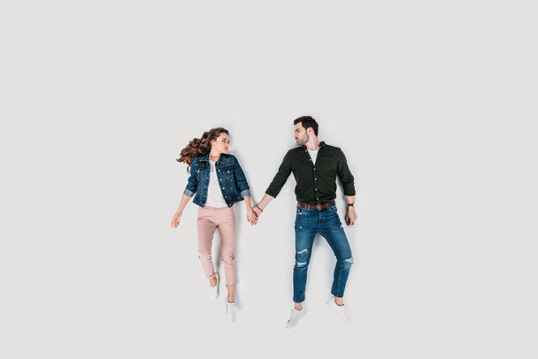 top view of stylish young couple holding hands isolated on white - Φωτογραφία, εικόνα